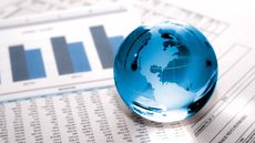 small glass globe on top of different financial papers