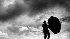 A man holds an umbrella on a cloudy day.