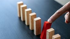 person removing red block from row of tan blocks