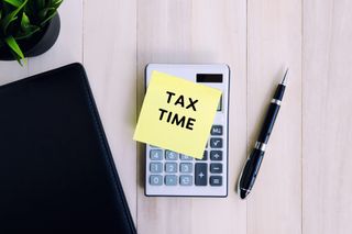 the words tax time on yellow post it note on top of calculator